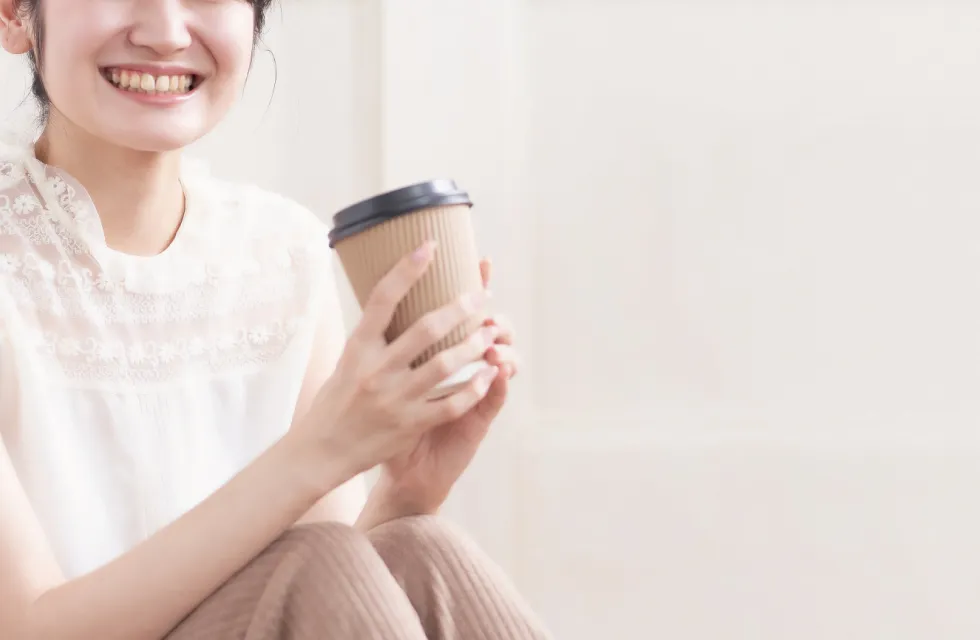 コーヒーカップを持つ笑顔の女性